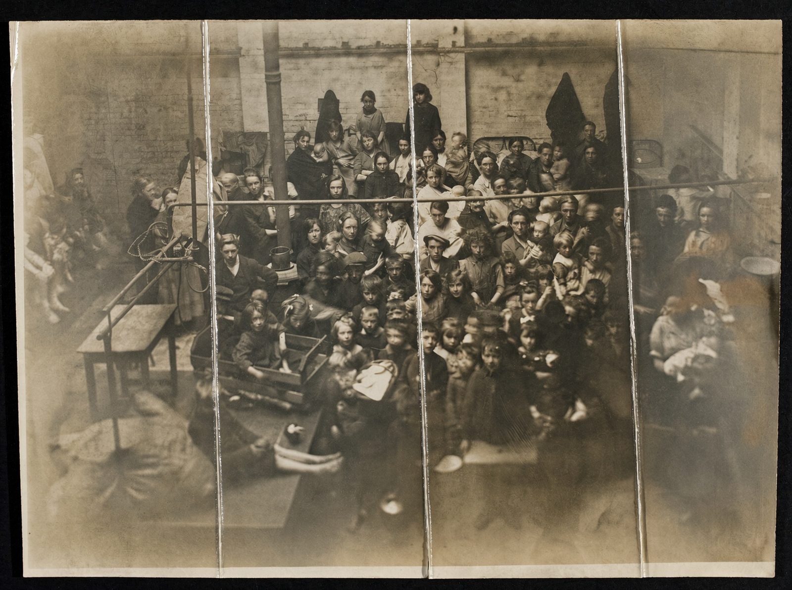A crowded hall of people seated on benches inside an Irish workhouse.